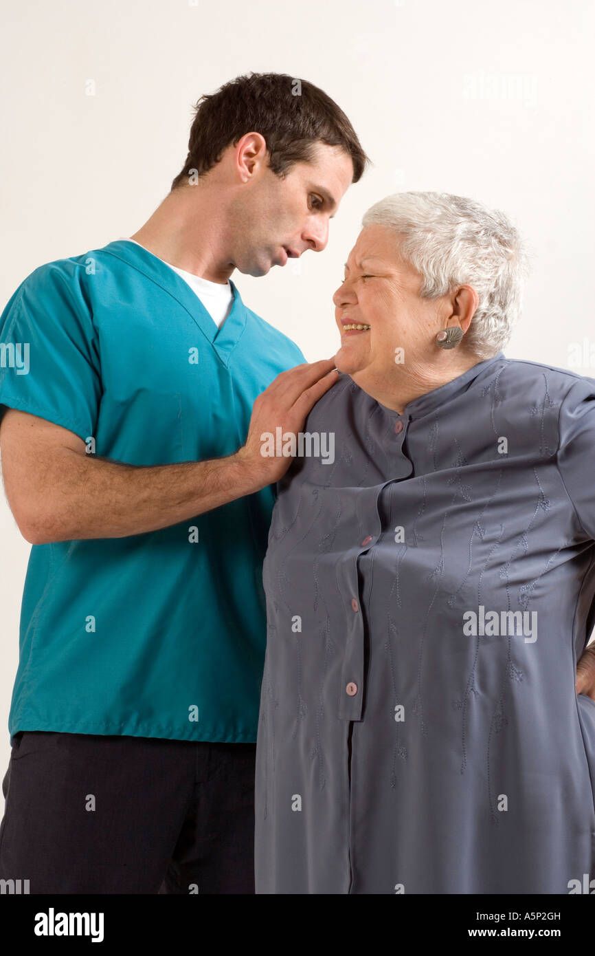 Krankenpfleger oder Arzt prüft älteren Patienten Schmerzen im Rücken. Stockfoto