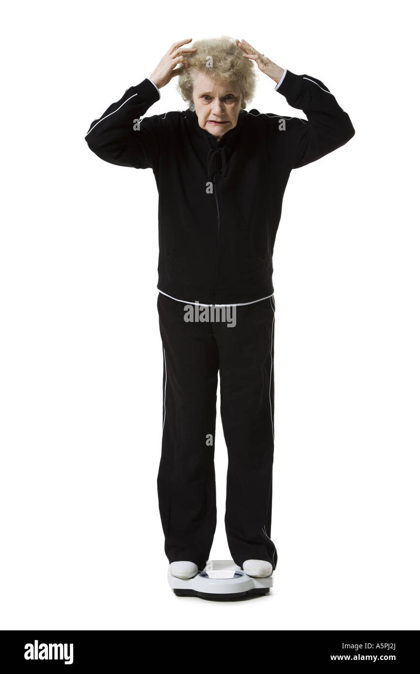 Ältere Frau mit einem Gewicht von selbst auf eine Personenwaage Stockfoto