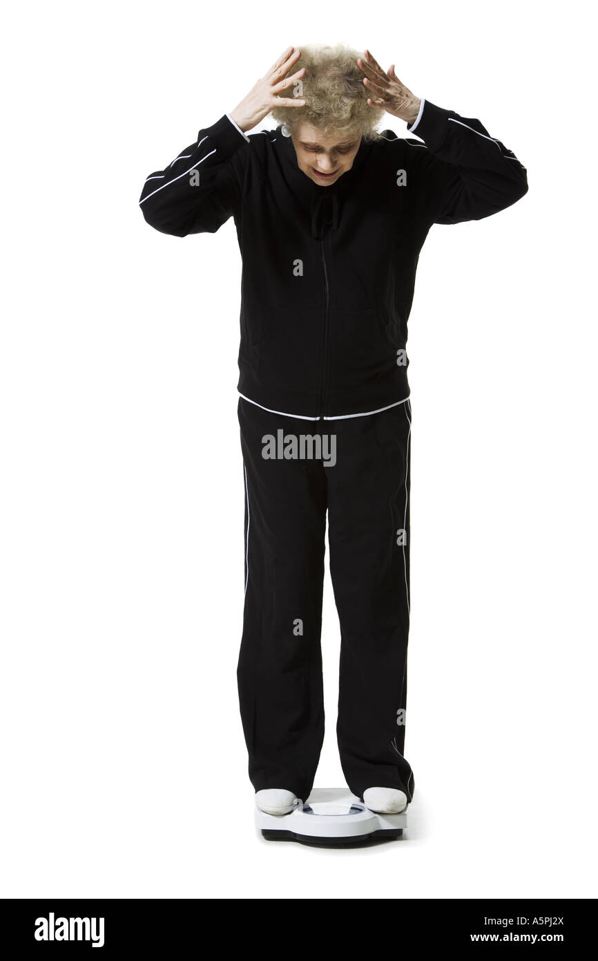 Ältere Frau mit einem Gewicht von selbst auf eine Personenwaage Stockfoto