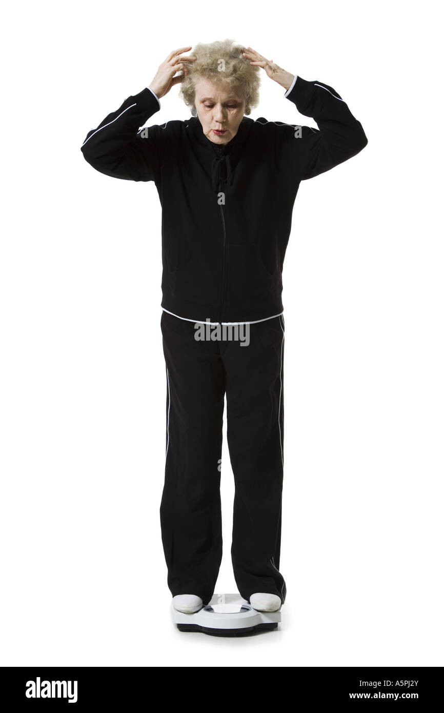 Ältere Frau mit einem Gewicht von selbst auf eine Personenwaage Stockfoto