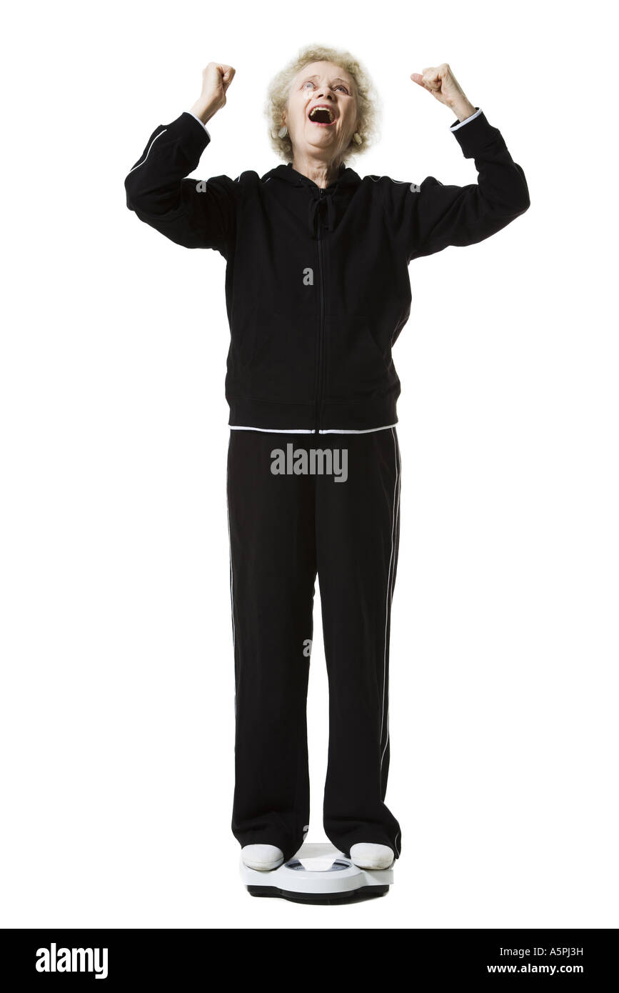 Ältere Frau mit einem Gewicht von selbst auf eine Personenwaage Stockfoto