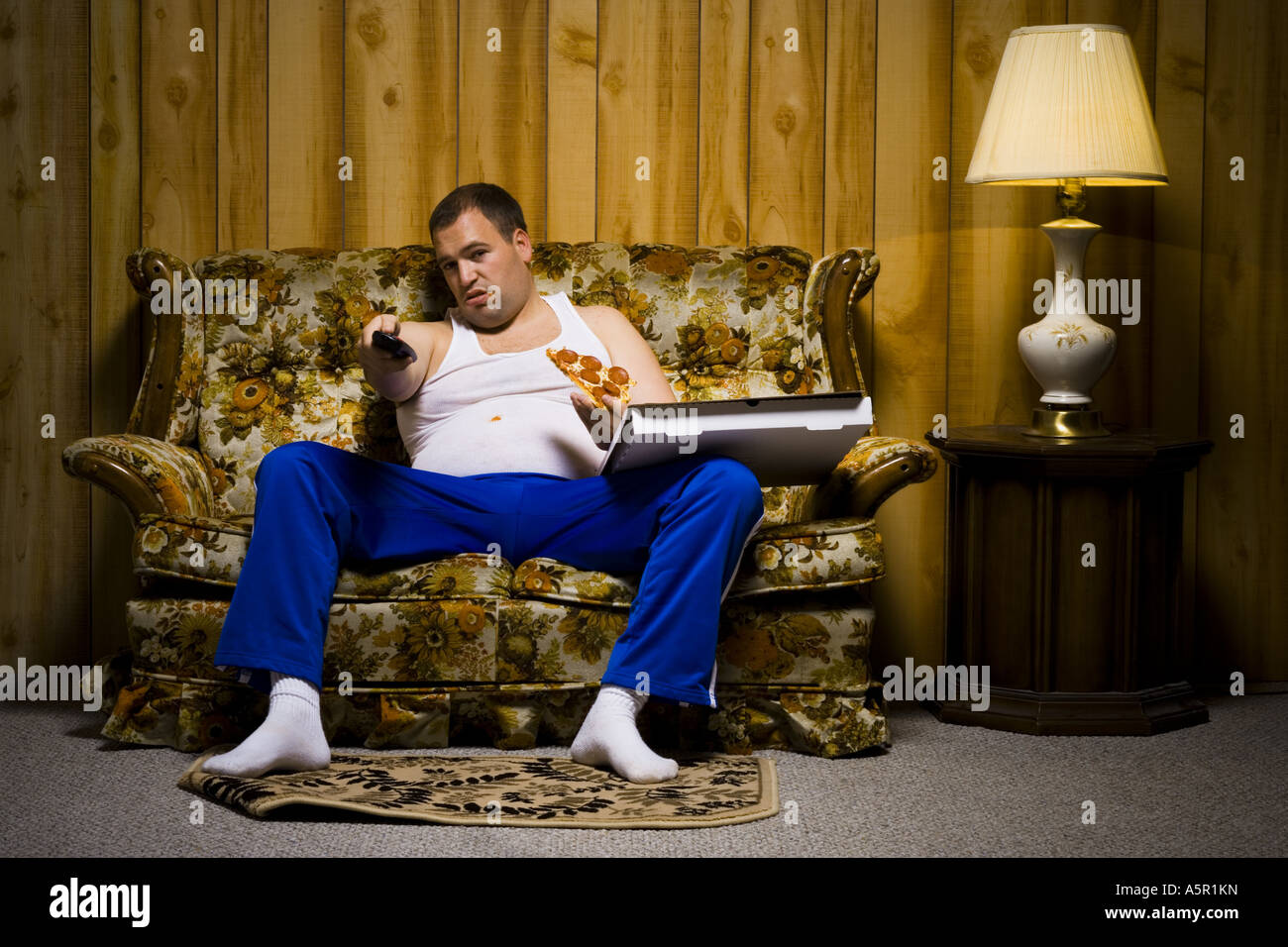 Mann auf Sofa mit Pizza und TV-Fernbedienung Stockfoto