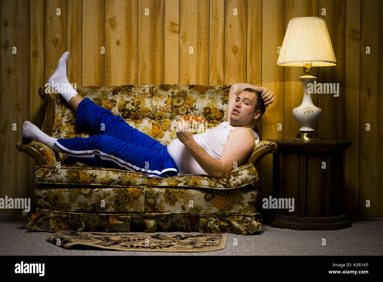 Mann auf Sofa mit Pizza und TV-Fernbedienung Stockfoto