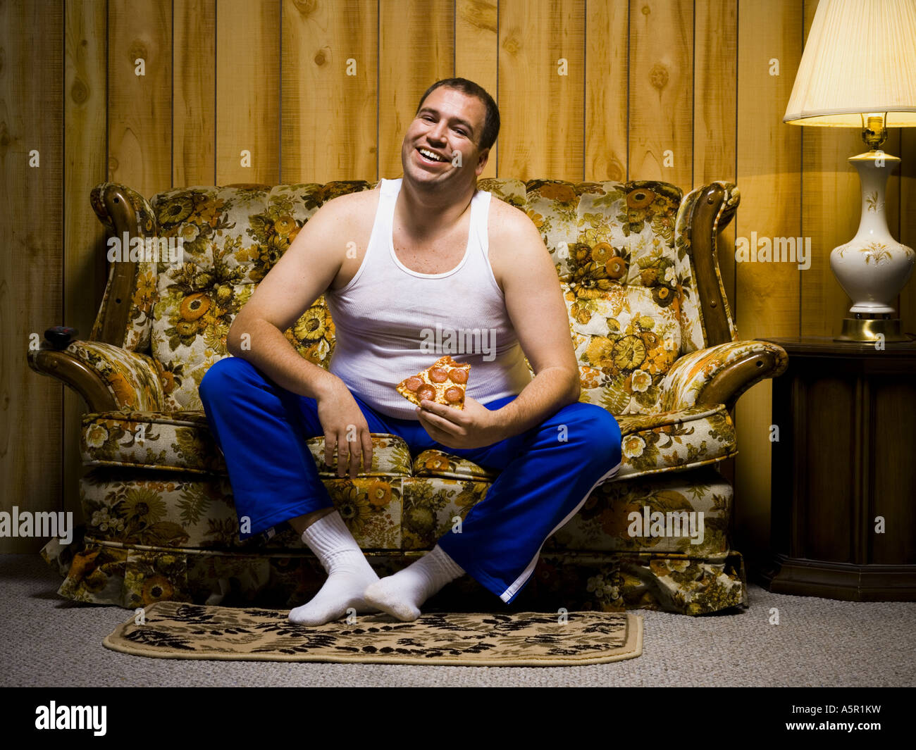 Mann auf Sofa mit Pizza und TV-Fernbedienung Stockfoto