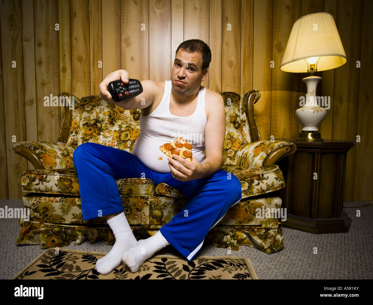 Mann auf Sofa mit Pizza und TV-Fernbedienung Stockfoto