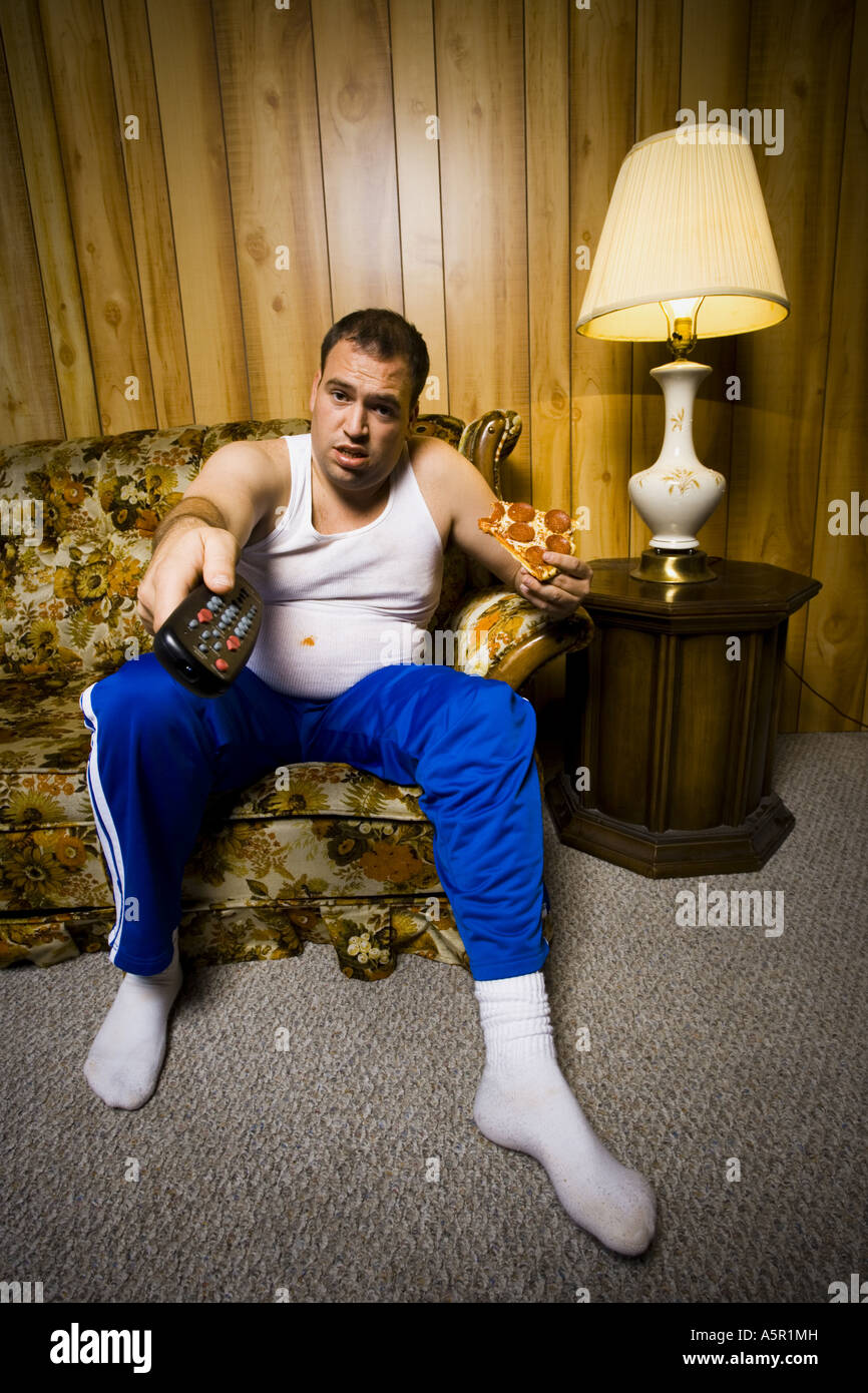Mann auf Sofa mit Pizza und TV remote lächelnd Stockfoto