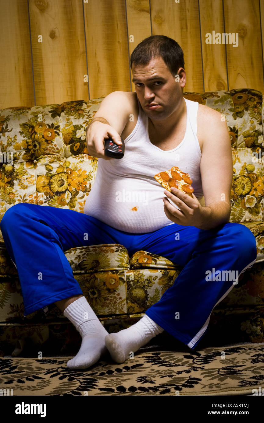 Mann auf Sofa mit Pizza und TV remote lächelnd Stockfoto