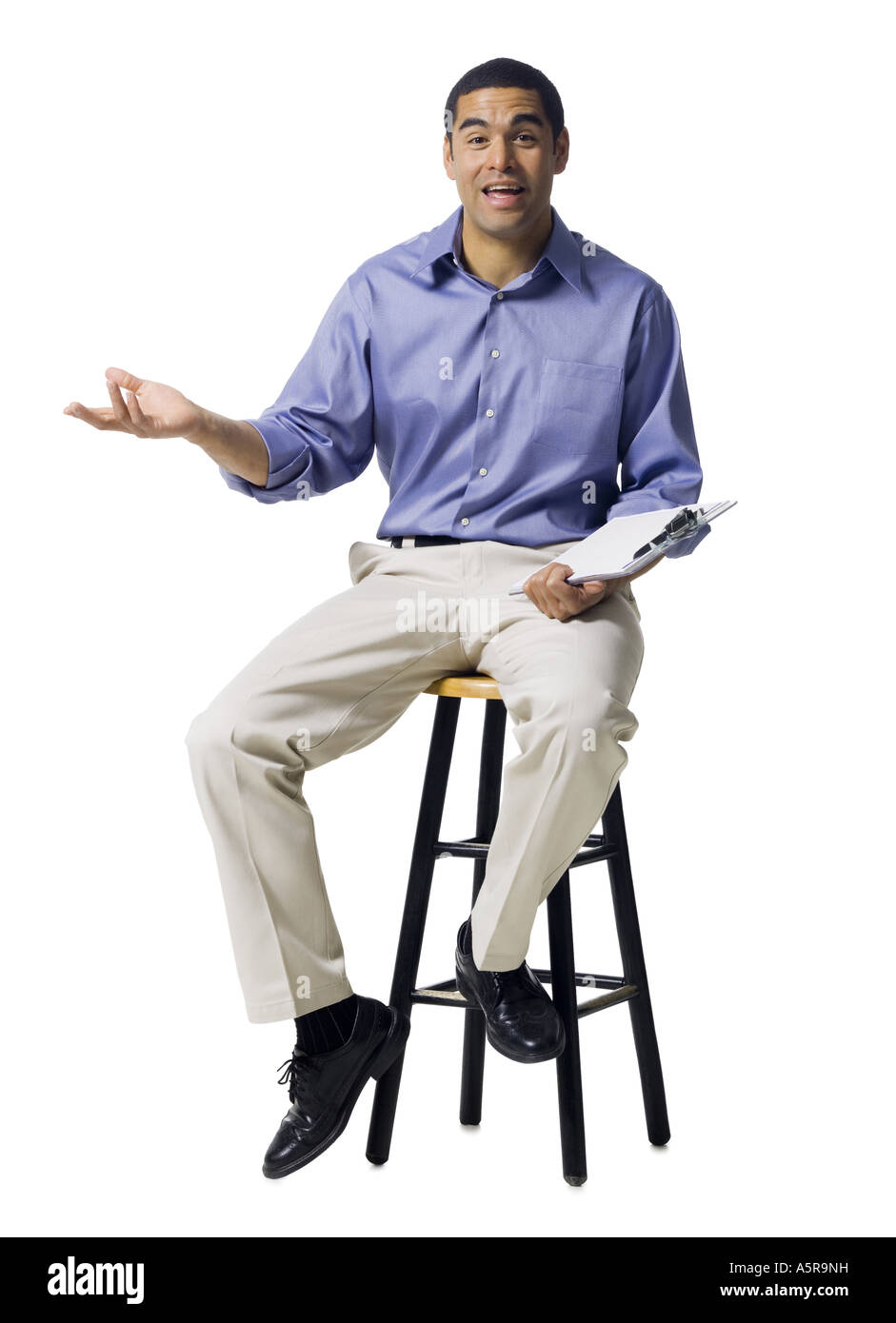 Mann sitzt auf einem Hocker mit Zwischenablage gestikulieren Stockfoto