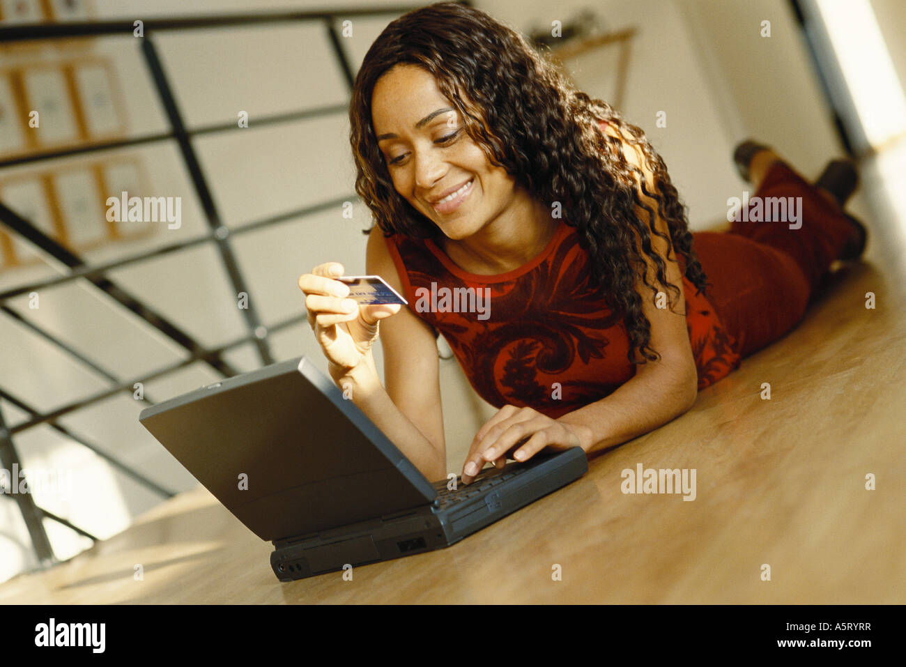 Junge Frau lag auf Boden mit Laptop, Holding, Kreditkarte Stockfoto