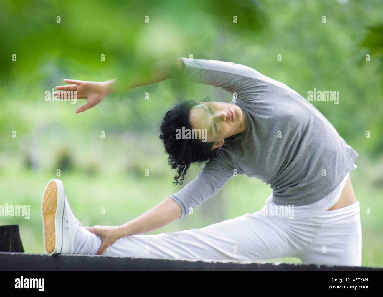 Junge Frau tun Seite Strecke am Holzzaun Stockfoto