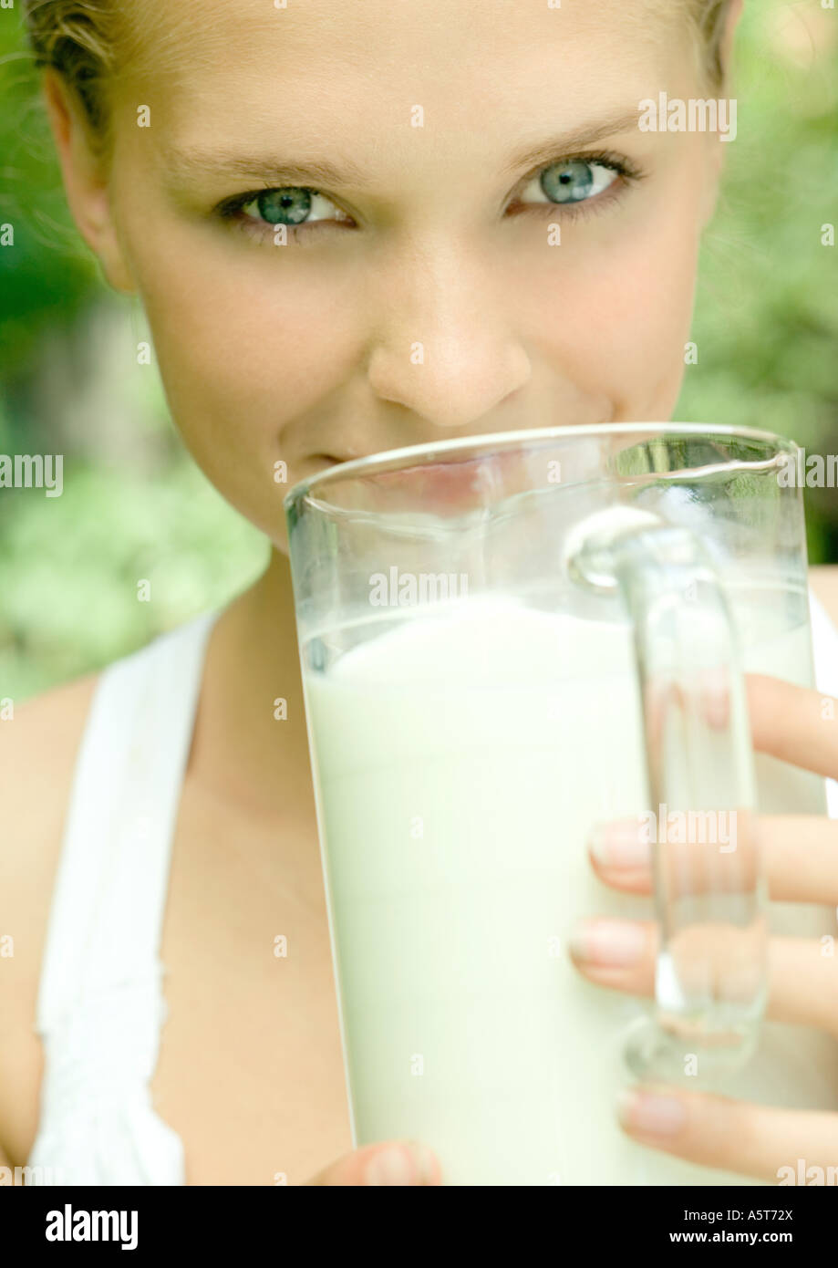 Junge Frau mit Krug Milch in den Mund Stockfoto