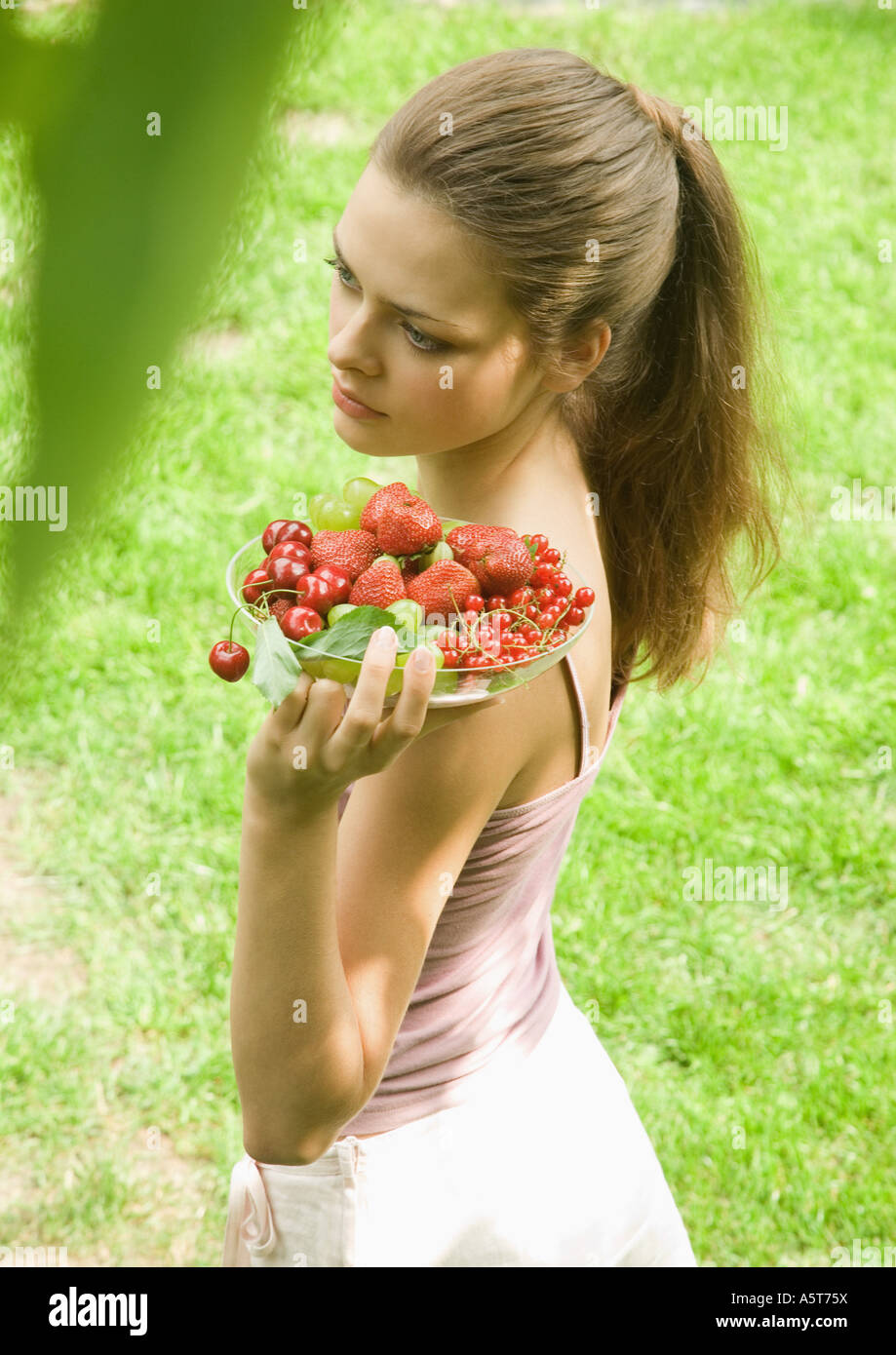 Junge Frau hält Obstschale Stockfoto