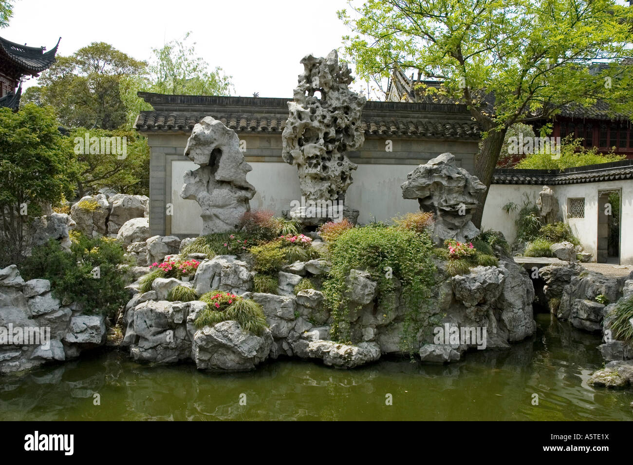 Stilisierten chinesischen Steingarten (Bildung) eingebettet mit blühenden Pflanzen am Ende von einem See, Yu-Yuan-Garten, Shanghai Stockfoto