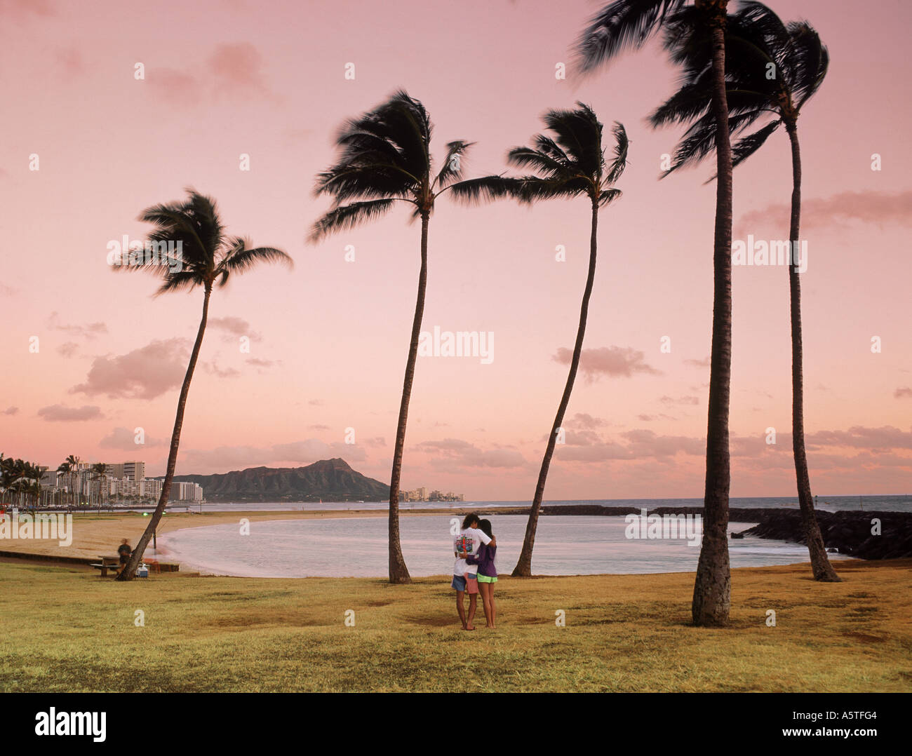 Paar auf Magic Island bei Sonnenuntergang mit Waikiki Beach und Diamond Head jenseits Stockfoto