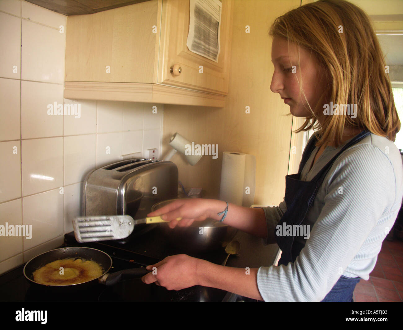 Junges Mädchen Kochen Pfannkuchen in Küche Stockfoto