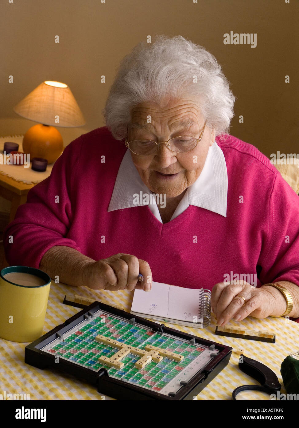 Ältere Dame genießt eine Geist-Gehirn stimulierende Wortspiel durch natürliche Fensterlicht Stockfoto