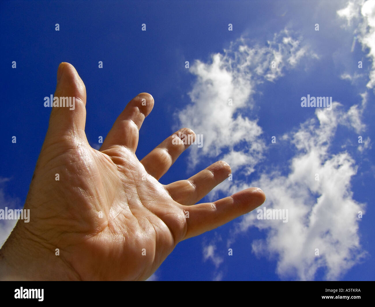 Männliche Hand dehnen bis ein blauer Himmel mit Wolken Stockfoto