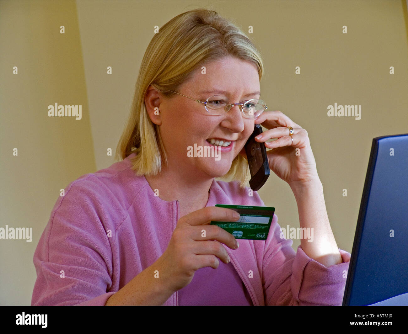 Frau am Telefon benutzt gerne ihre Kreditkarte, um online mit ihrem Laptop-Computer-shop Stockfoto