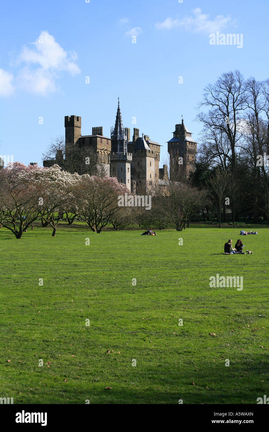 Cardiff Castle und Bute park paar im Park mit Schloss und Bäume hinter ihnen sitzen. Frühlingszeit. Stockfoto