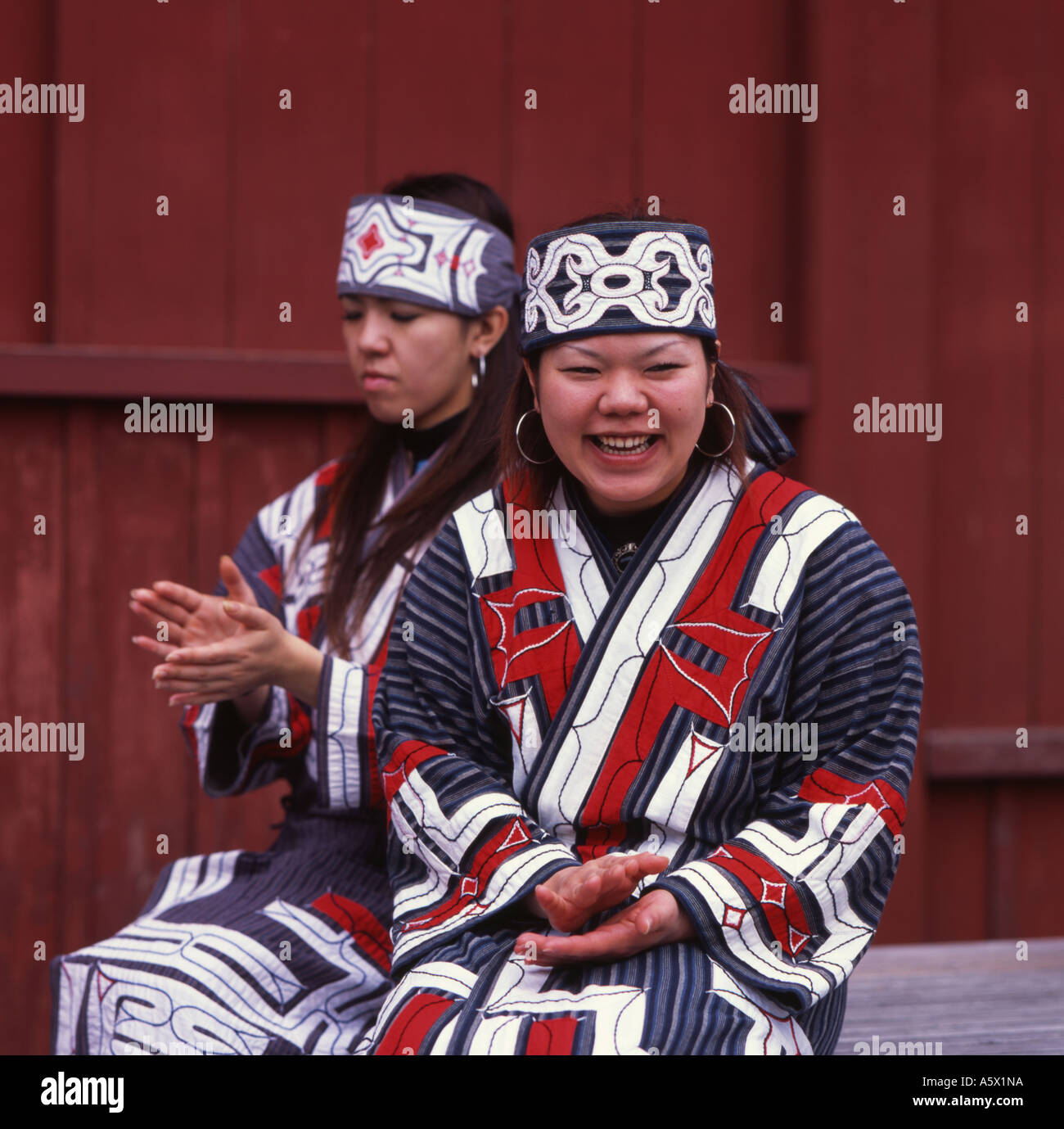 Lächelnde Ainu Mädchen in traditioneller Tracht Stockfoto