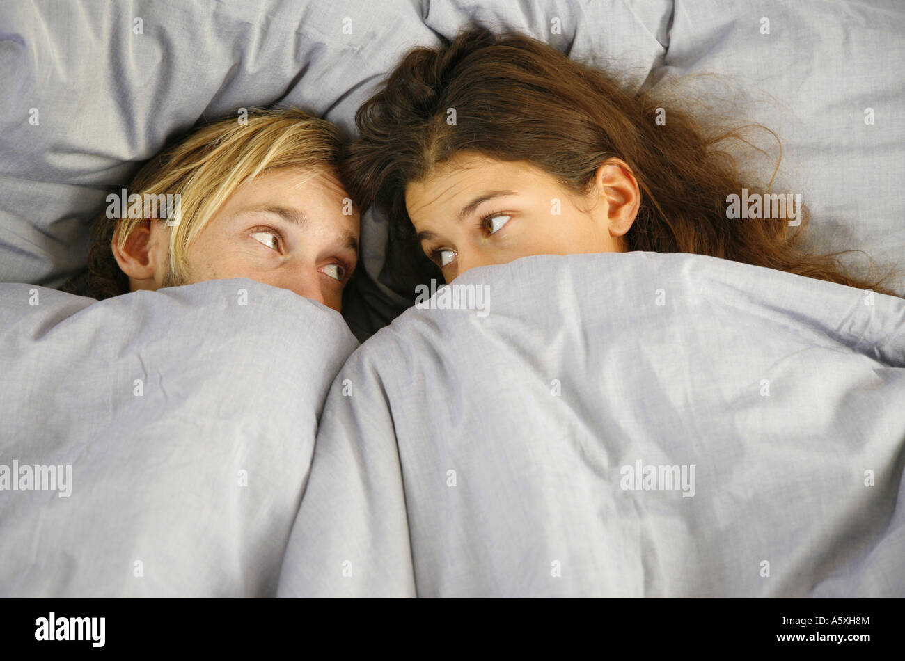 Junges Paar auf Bett sahen einander erhöhten Blick Stockfoto