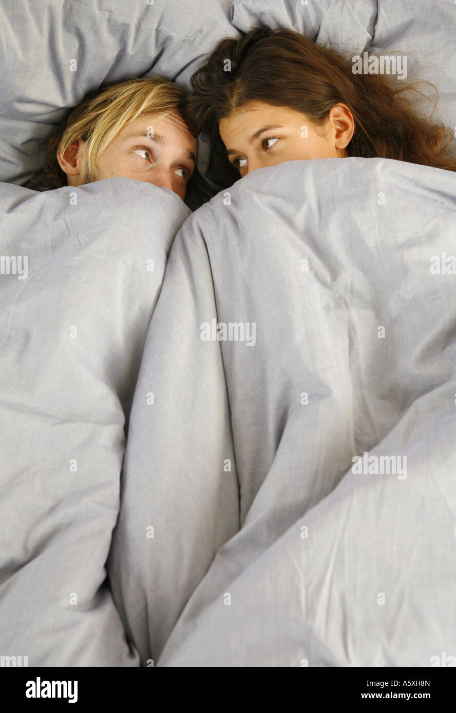 Junges Paar auf Bett sahen einander erhöhten Blick Stockfoto