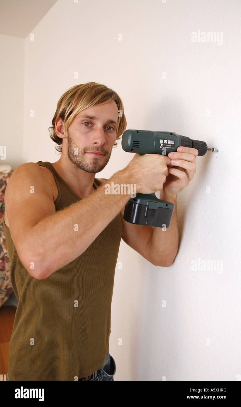 Junger Mann Schrauben Schraube in die Wand Porträt hautnah Stockfoto