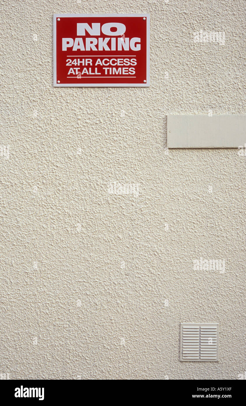 Roten und weißen Schild hoch oben auf einer Creme lackiert gerendert Wand besagt keine Parkplätze 24 Stunden Zugang zu allen Zeiten Stockfoto