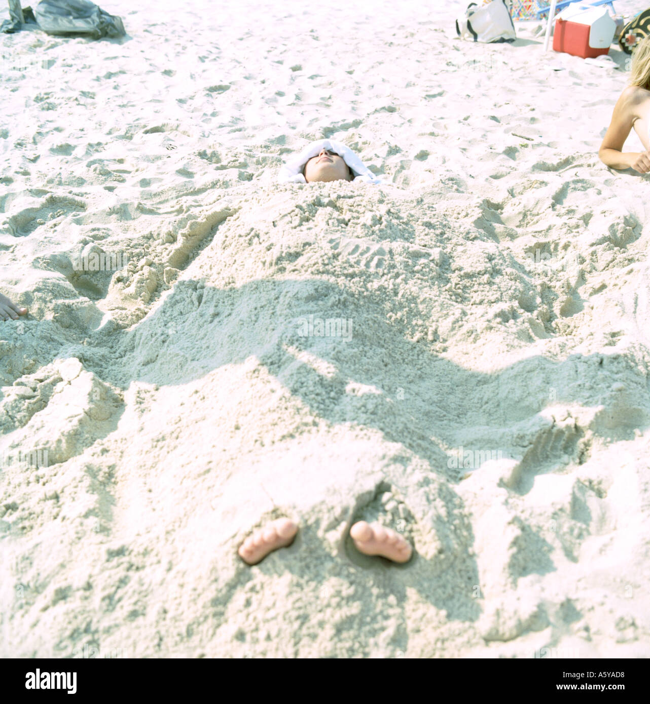 Beachboy Szene bedeckt mit Sand, die die Zehen ragen sind Stockfoto