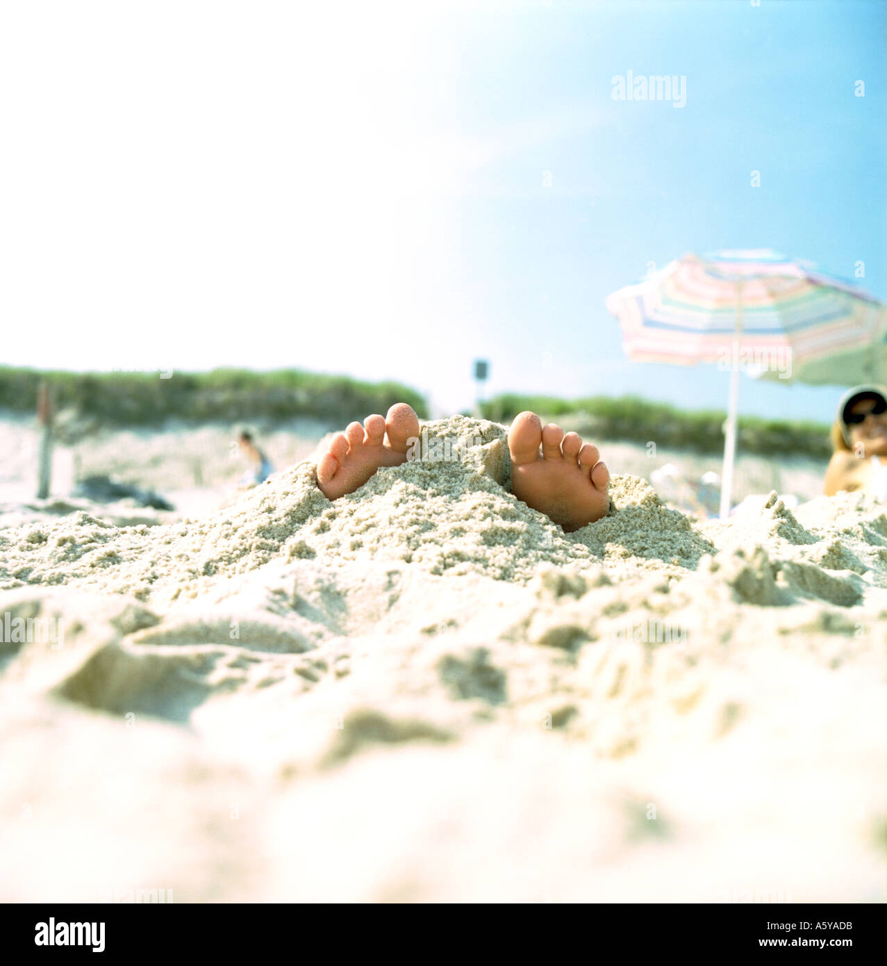 Beachboy Szene bedeckt mit Sand, die die Zehen ragen sind Stockfoto