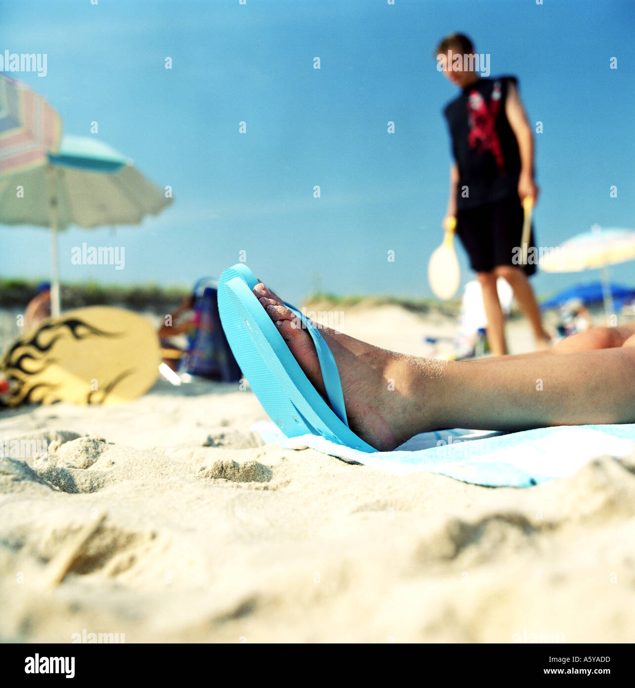 Strand-Szene im Hintergrund ein Teenager auf der Vorderseite sieht man Frau s Füße in flip flops Stockfoto