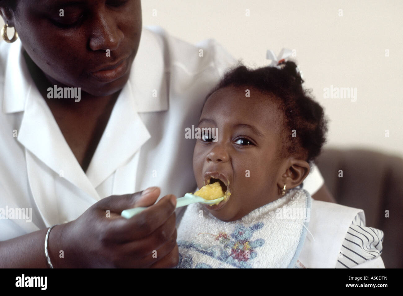 Schwarze Mutter Löffel füttern Baby Tochter. Stockfoto