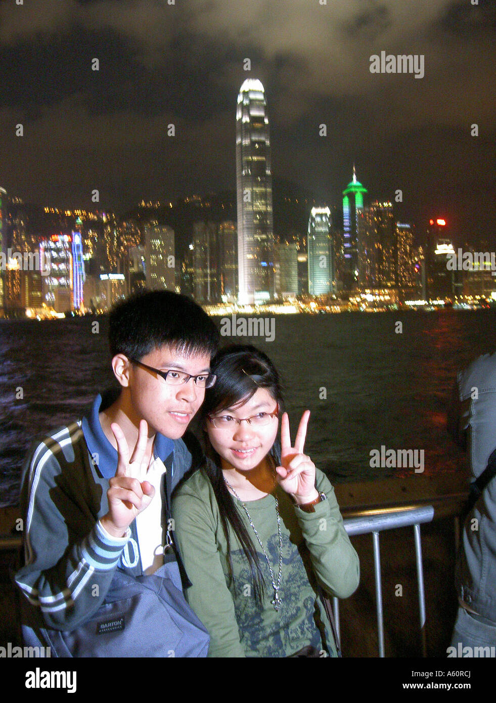 Chinesisches Paar für Fotos zu posieren. Hong Kong Skyline. Höchsten ist Two International Finance Centre gesehen über dem Hafen von Kowloon Stockfoto