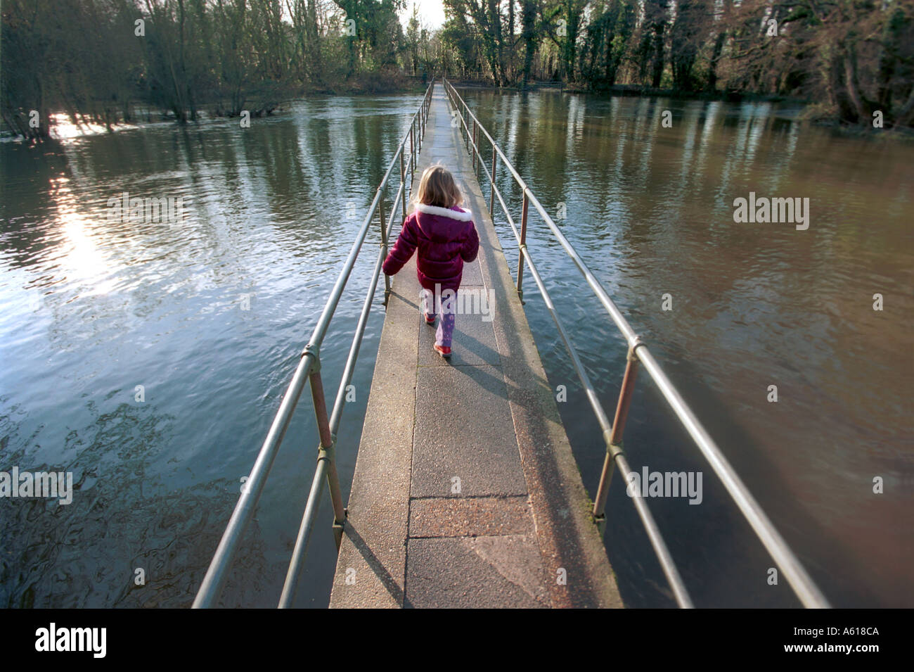 Ein kleines Kind auf einer Brücke überquert über einen Fluss Stockfoto