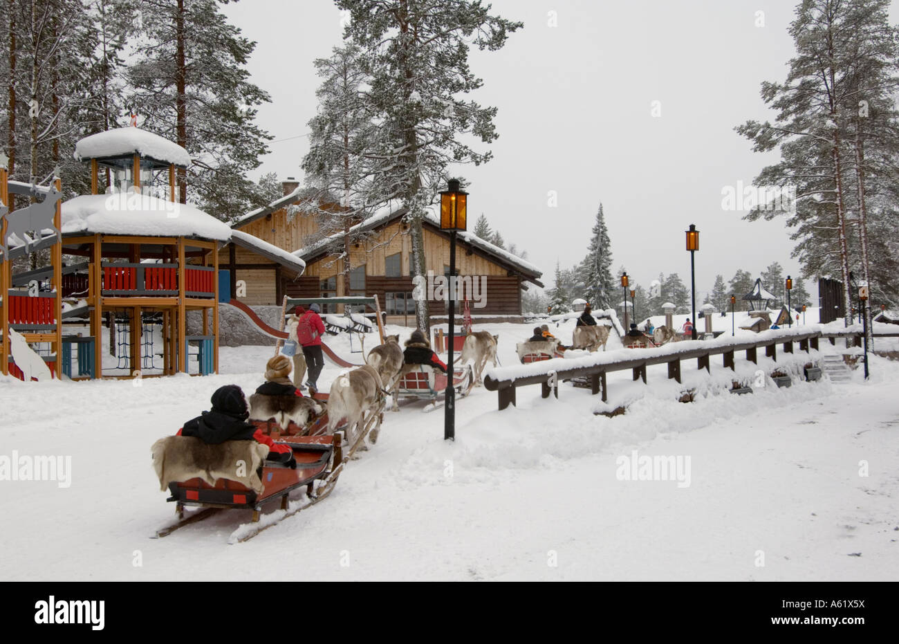 Touristen in Schlitten, gezogen von Rentieren, Santa Claus Village, Rovaniemi, Lappland, Finnland, Europa, Arktis Stockfoto