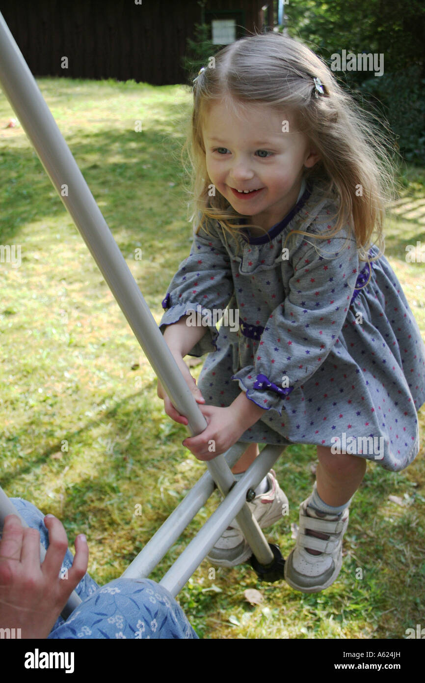 kleines Mädchen draußen spielen auf Schaukel Stockfoto