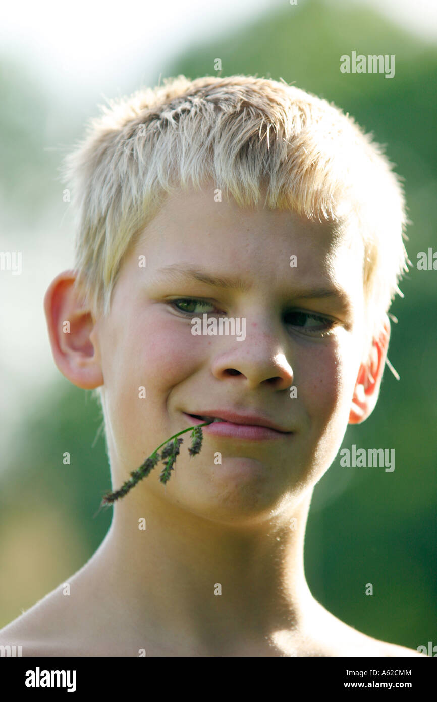 Porträt eines jungen verschmitzt aussehende fair mit einem Grashalm im Mund Stockfoto