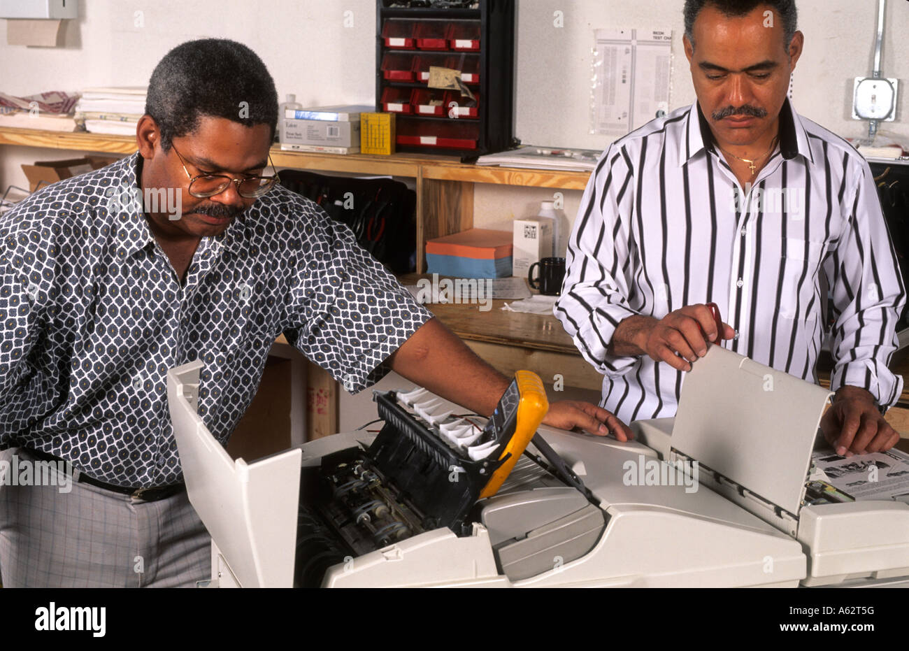 Schwarze afrikanische amerikanische Männer in Schwarz im Besitz Minderheit Geschäftslage Reparatur Kopierer im Büro Stockfoto