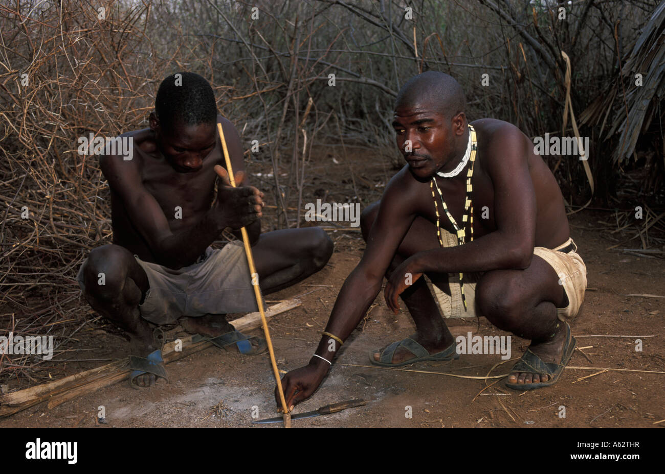 Hadza Mann, der ein Feuer mit einem Stock und Stein Lake Eyasi Tansania kleine Stamm der Jäger und Sammler Stockfoto