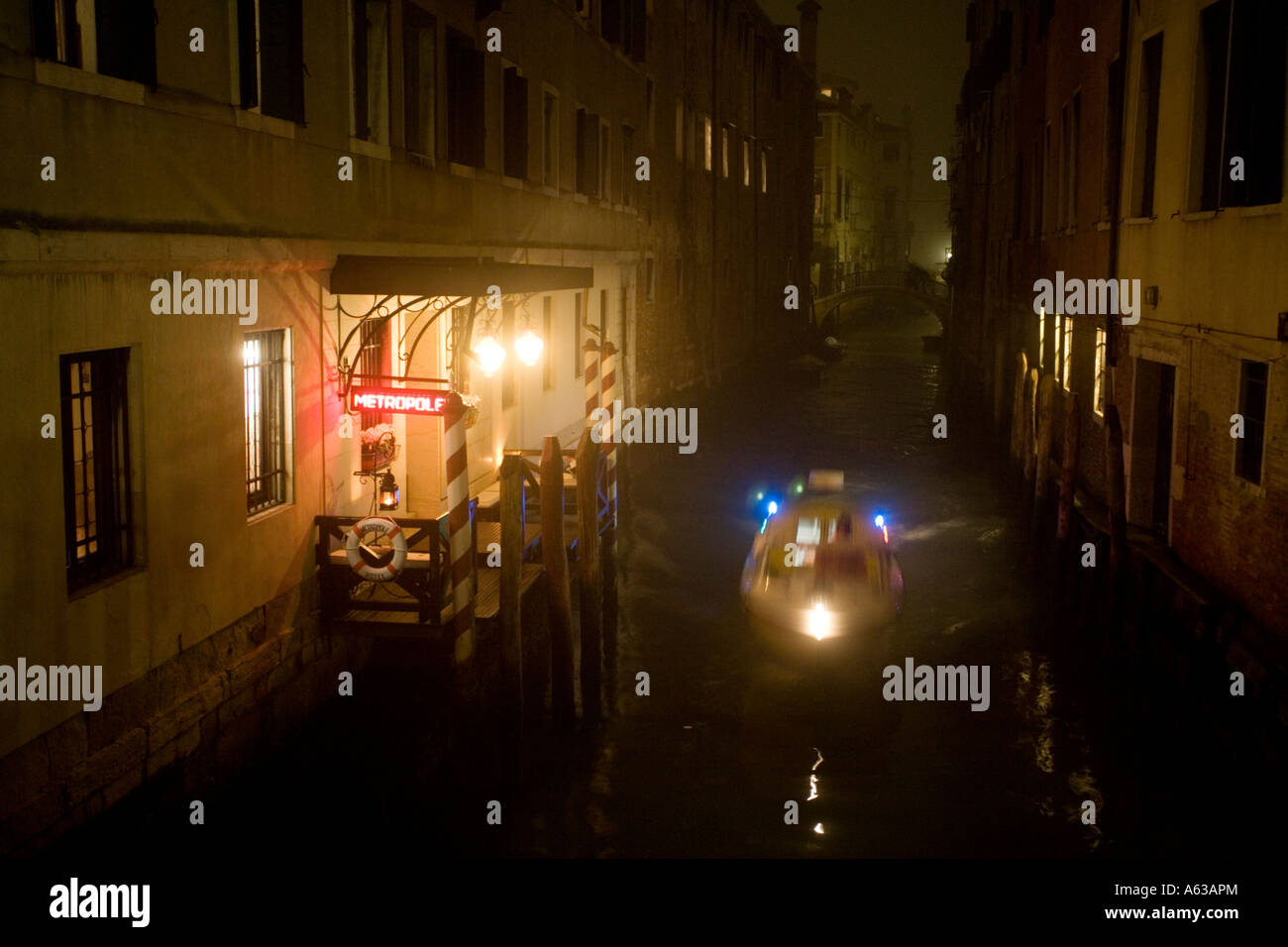 Ein Polizeiboot blau leuchtet blinkende Reisen an einem Kanal entlang vorbei an im Hotel Metropole in einer nebligen Nacht in Venedig Stockfoto