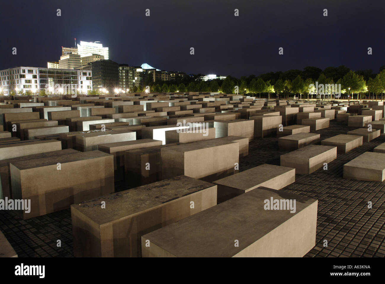 Nachts beleuchtet konkrete Stelen am Denkmal mit Gebäude im Hintergrund, Holocaust-Mahnmal, Berlin, Deutschland Stockfoto