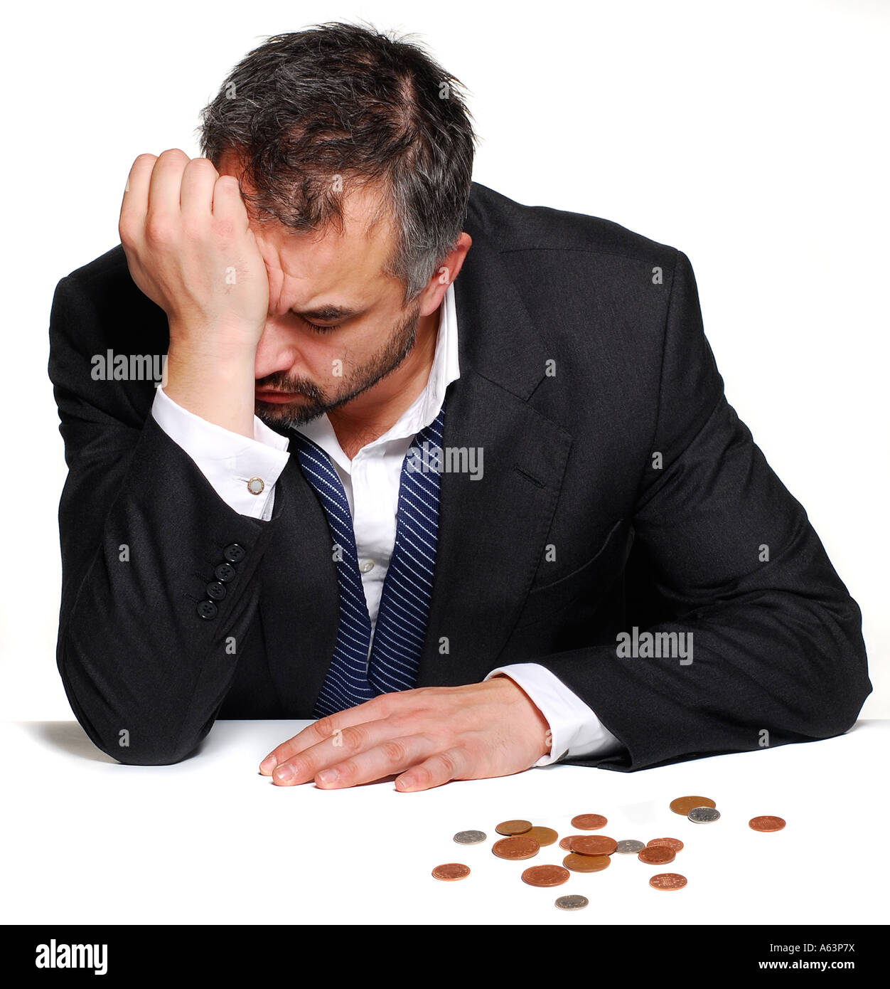 Ein emotionaler Mann sitzt hielt seinen Kopf mit seinen Händen mit seinem letzten paar Groschen vor. Bild von Patrick Steel patricksteel Stockfoto