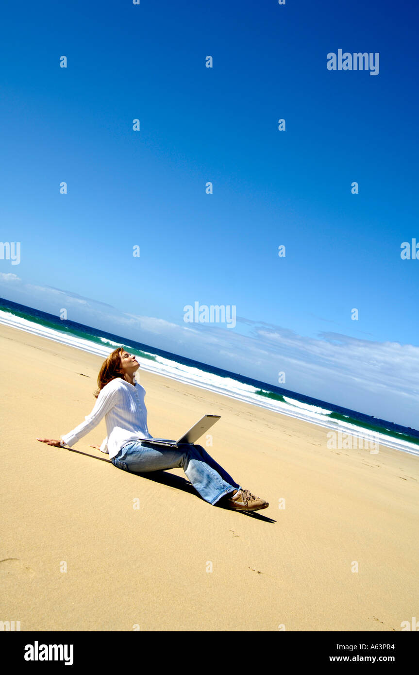 Frau mit Laptop am Strand sitzen Stockfoto