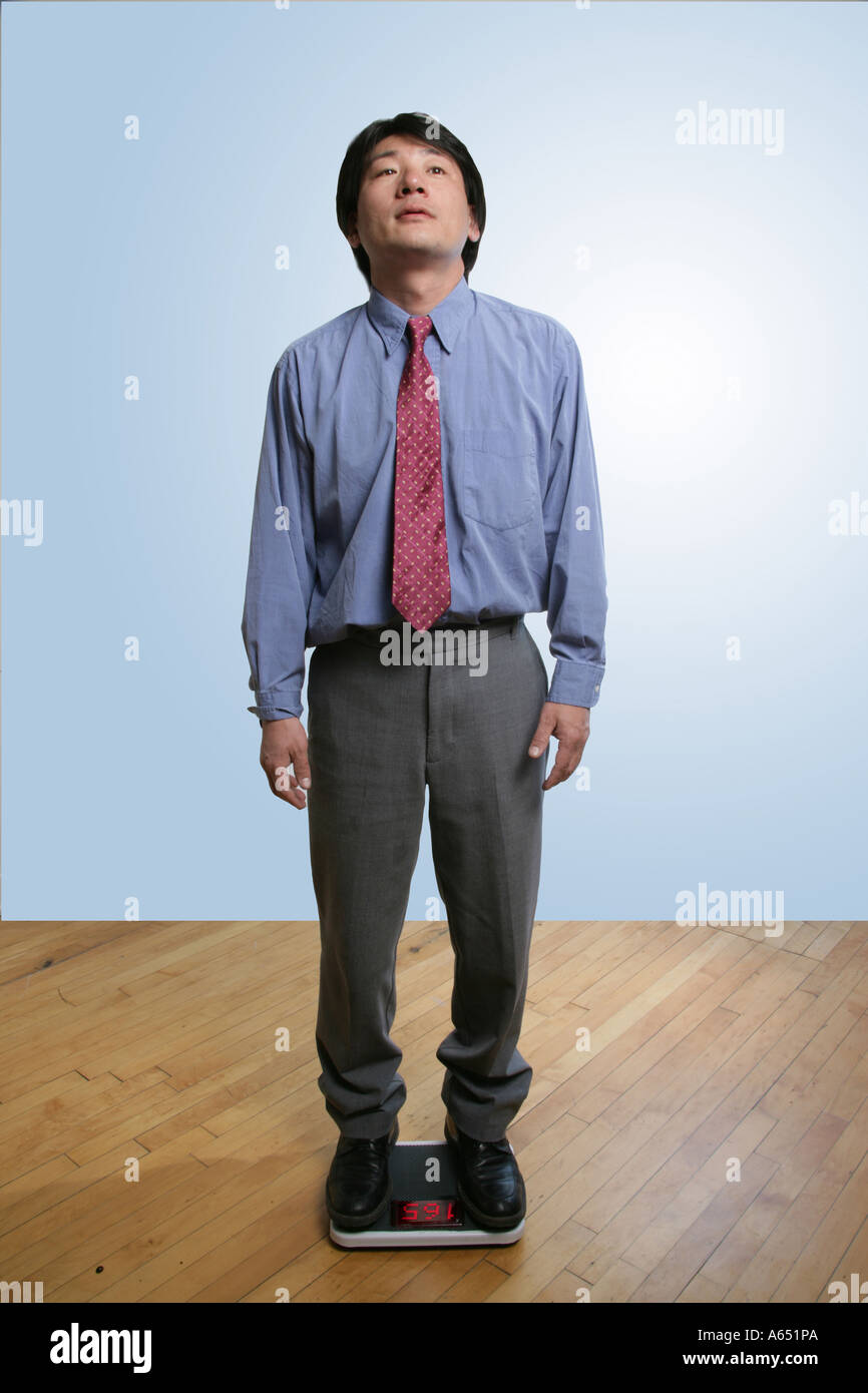 Asiatischen Mann auf Waage wiegen sich. Stockfoto