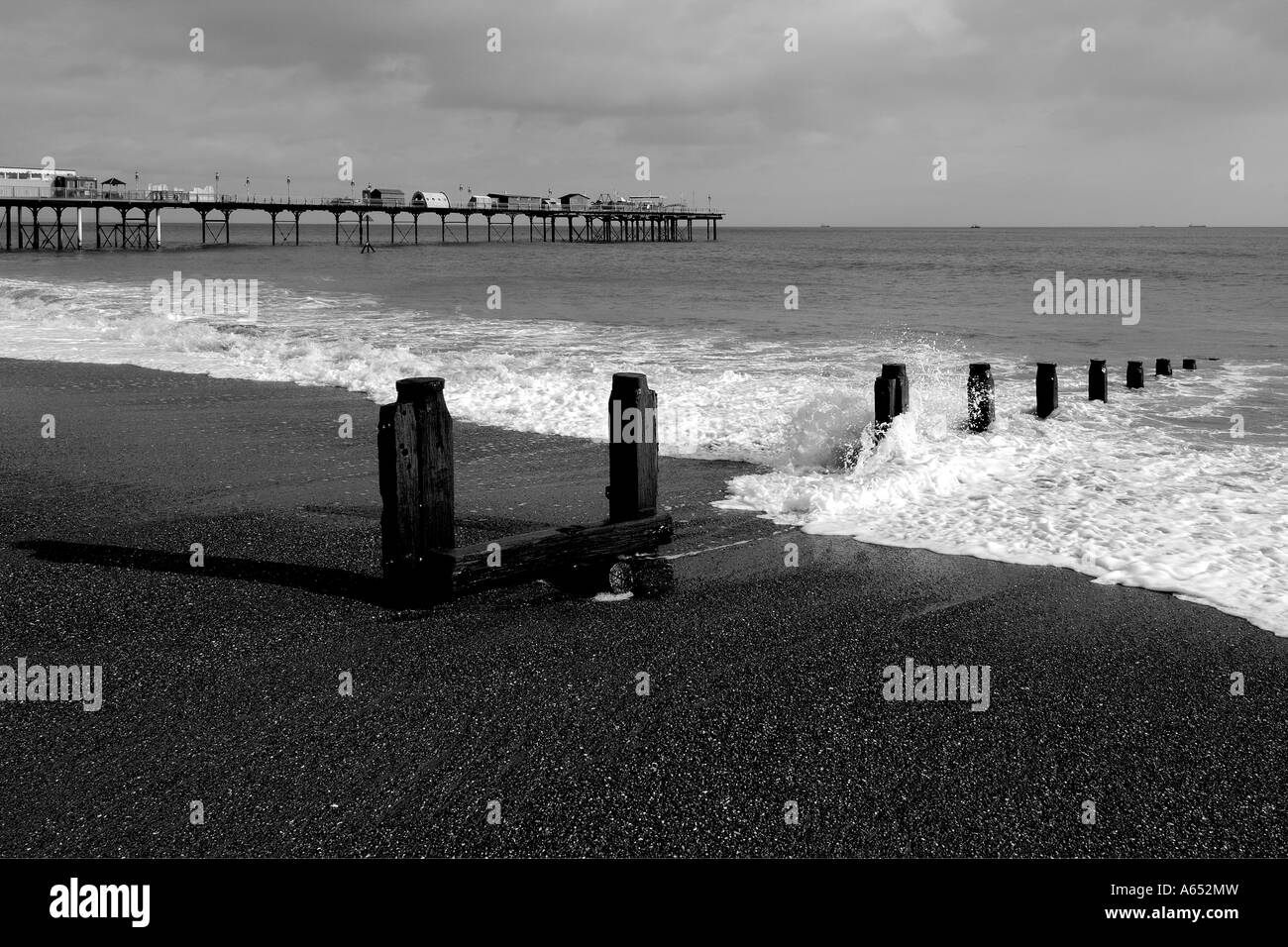 Monochromes Bild von Wellen, die über eine hölzerne Buhne auf dem Vorland in Teignmouth South Devon Stockfoto