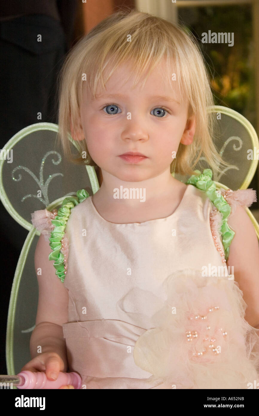 junge blonde Mädchen mit großen blauen Augen in einem rosa Kleid und Fee Flügel Stockfoto