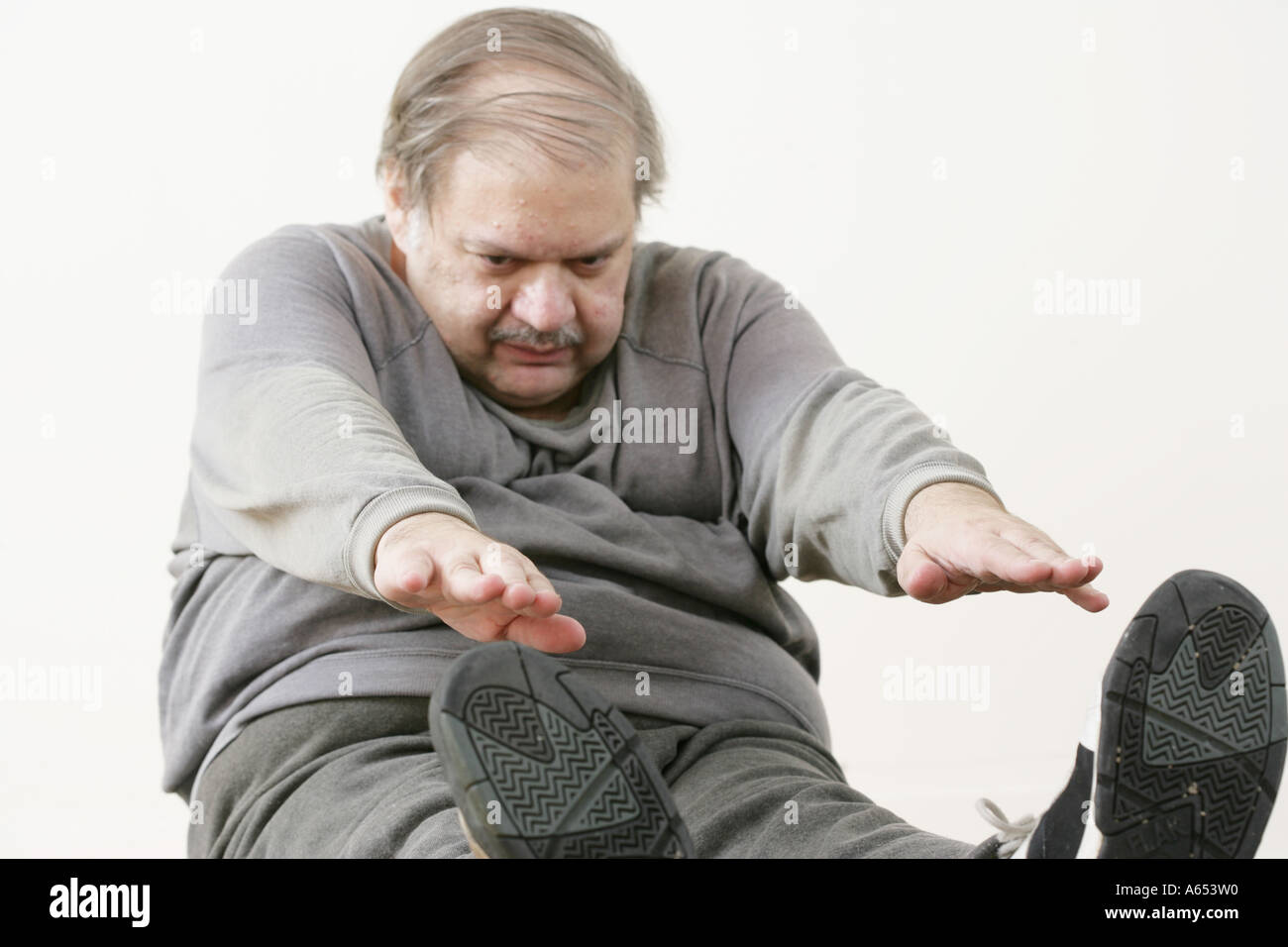 Übergewichtiger Mann streckt und macht Sit-Ups. Stockfoto