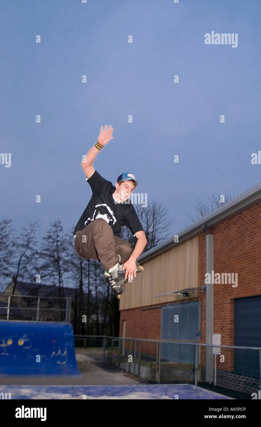 18 Jahre alte Männchen machen aggressive Inline skating Tricks in UK skatepark Stockfoto