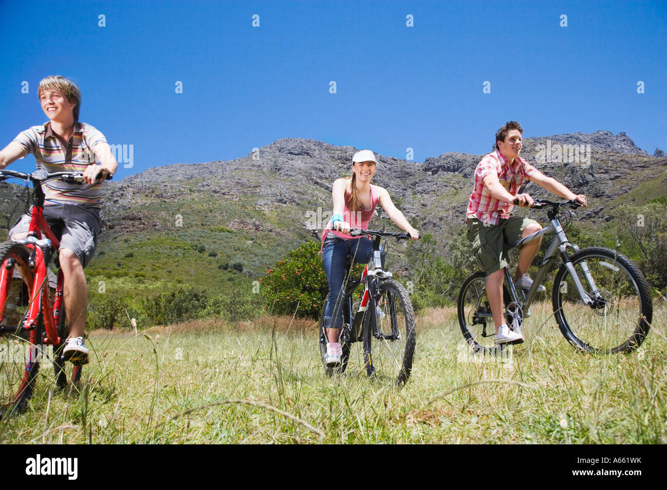 Zwei Teenager-Jungen und Mädchen (16-17 Jahre), Biken, Berge im Hintergrund Stockfoto