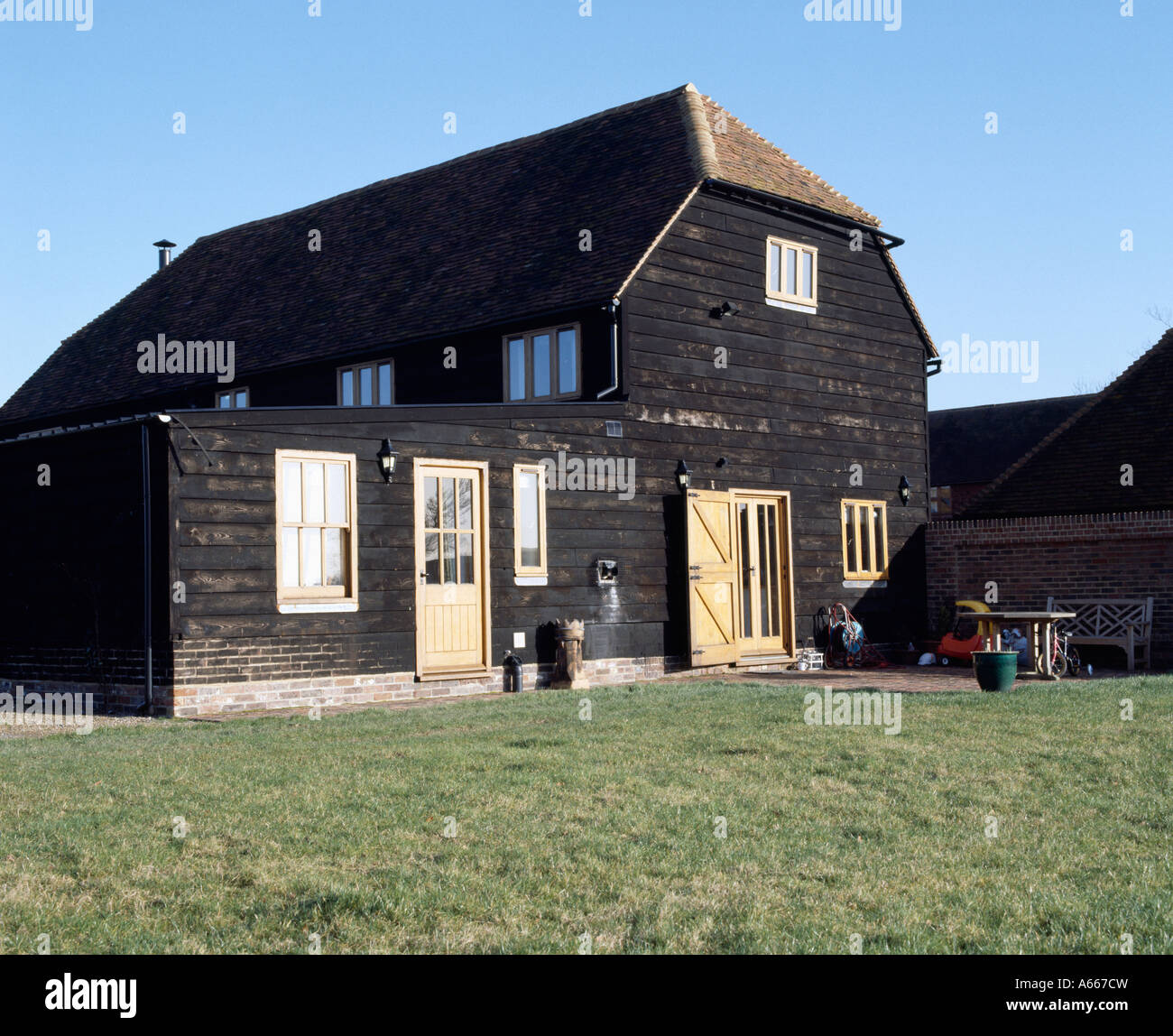 Hölzerne Scheune mit kleinen einstöckigen Erweiterung schwarz lackiert Stockfoto